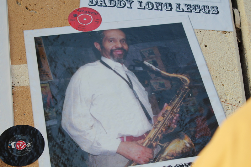 Mural photo of Rev David Hector holding a saxophone, with vinyl records displayed nearby.
