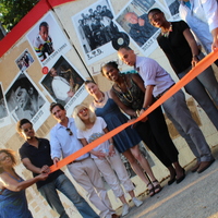 Group of people in front of the Mt. Hope Music Mural, cutting an orange ribbon at dedication ceremony.
