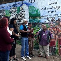 Dedication ceremony for the Land Acknowledgement Mural depicting the Pan-Indian Movement 1920, with community members gathered before it.