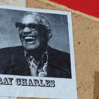 Black-and-white photo of Ray Charles laughing, wearing sunglasses, displayed on the music mural.
