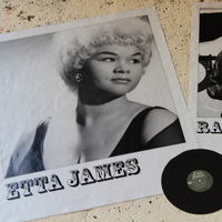 Black-and-white portrait of Etta James on textured wall, showing the singer looking to the side; a vinyl record and another musician photo nearby.
